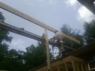 Carpenter setting a ridge beam over a new addition frame — Ice Dam Removal by Roofing Brothers in Hollister