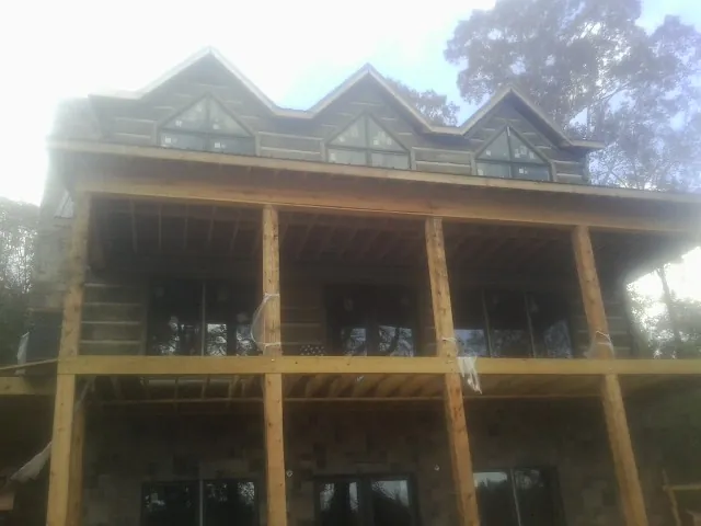 Dormers and porch framing on a large log home under construction — Roof Coating work by our crew in Hollister